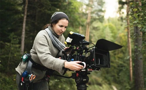 Mascha Deikova, operating a film camera, in a forest